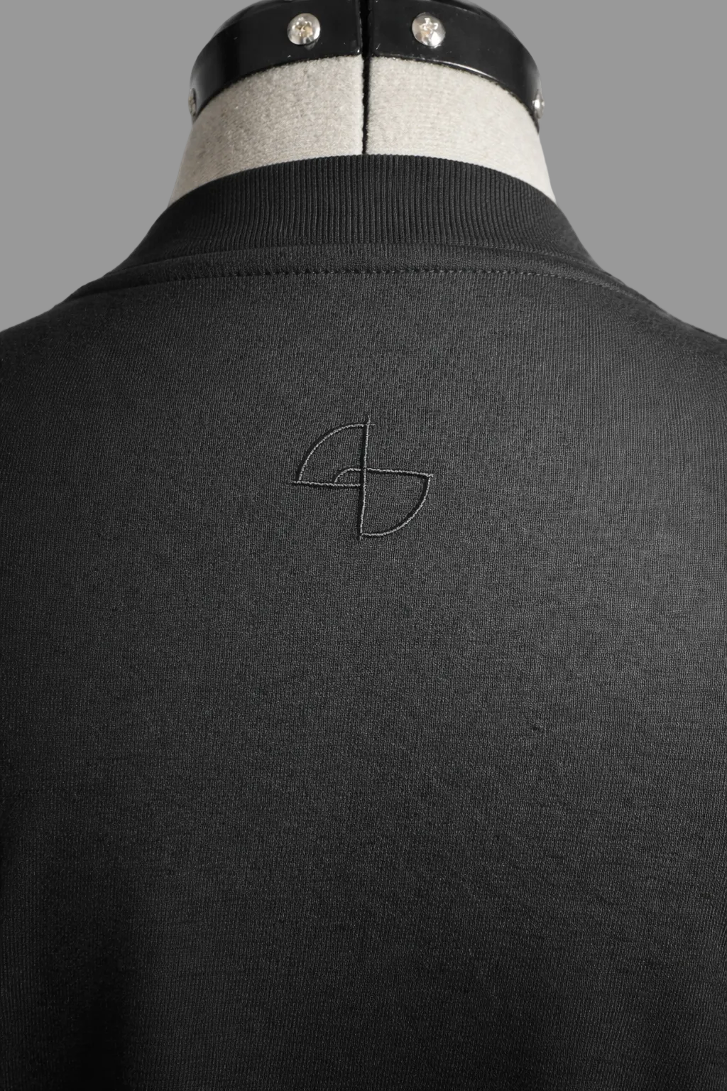 Close-up of subtle upper-back embroidery on black 215 gsm organic cotton T-shirt, ARC Exhibit 01 Vector